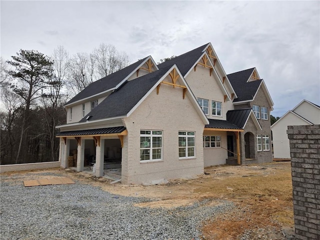 view of front facade with a standing seam roof, brick siding, and metal roof