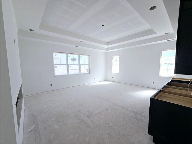 unfurnished living room featuring a wealth of natural light and a tray ceiling