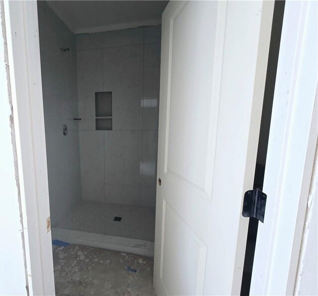 bathroom with marble finish floor and a tile shower