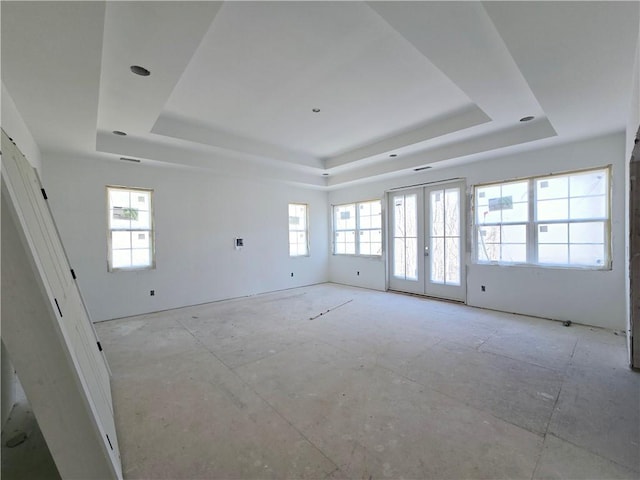 spare room featuring plenty of natural light, a raised ceiling, and french doors