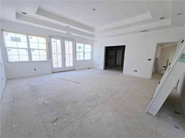 interior space with visible vents, a tray ceiling, and french doors