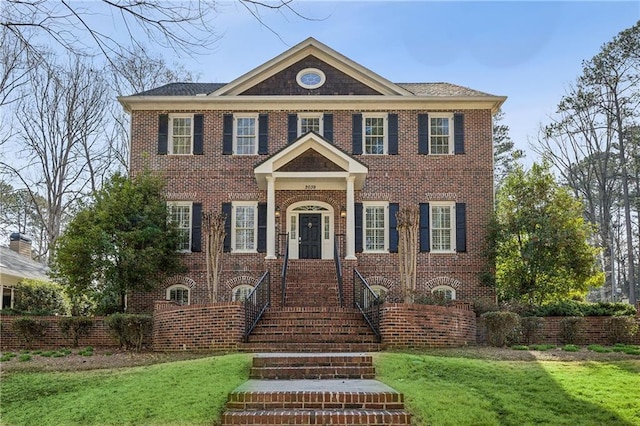 georgian-style home featuring brick siding and a front lawn