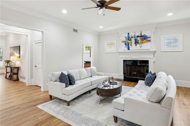 living room with a ceiling fan, recessed lighting, crown molding, light wood finished floors, and baseboards