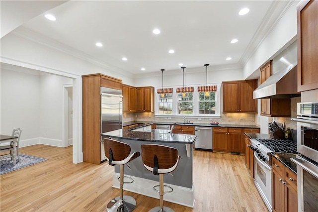 kitchen with a kitchen island, crown molding, a kitchen bar, light wood-style floors, and stainless steel appliances