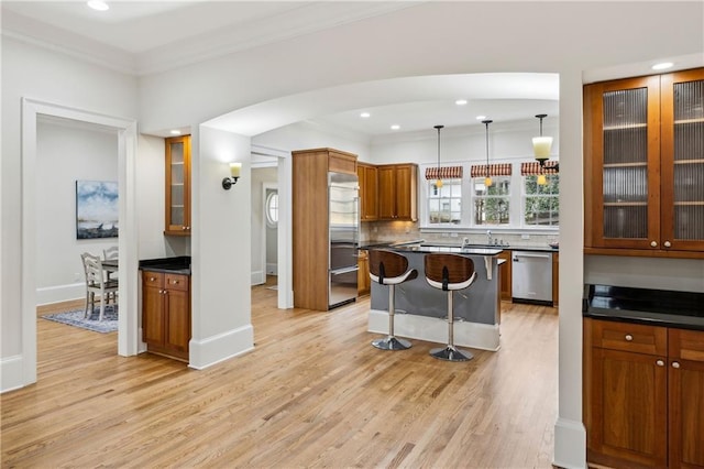 kitchen with a breakfast bar, light wood-style floors, brown cabinets, and appliances with stainless steel finishes