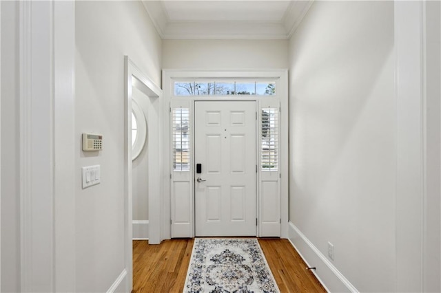 foyer entrance with baseboards, light wood-style flooring, and ornamental molding