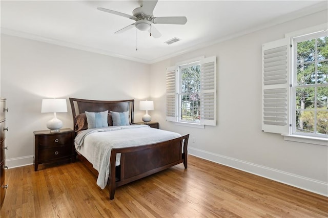 bedroom featuring baseboards, multiple windows, wood finished floors, and ornamental molding