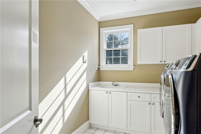 washroom featuring light tile patterned floors, cabinet space, a sink, crown molding, and washer and clothes dryer