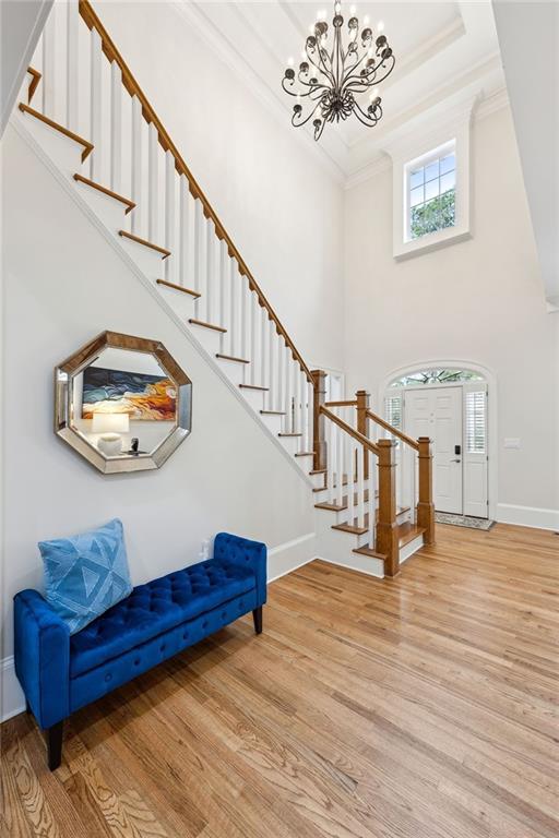 entrance foyer featuring baseboards, a chandelier, light wood-type flooring, stairs, and ornamental molding