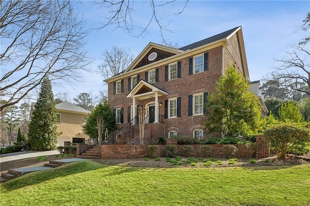 colonial inspired home featuring a front lawn and brick siding