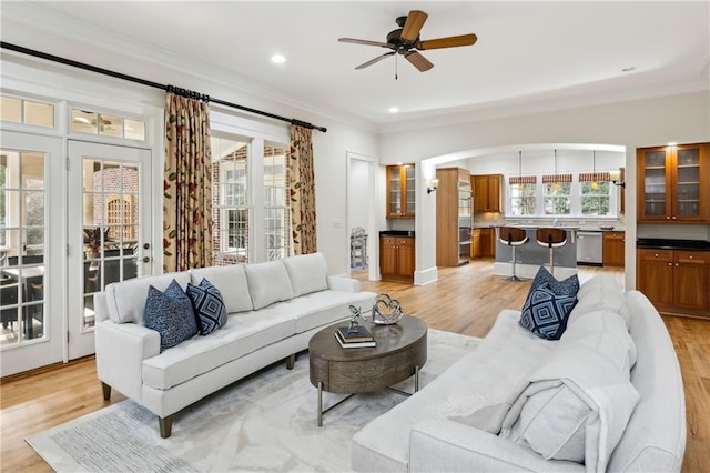 living area featuring a ceiling fan, light wood-style floors, and ornamental molding