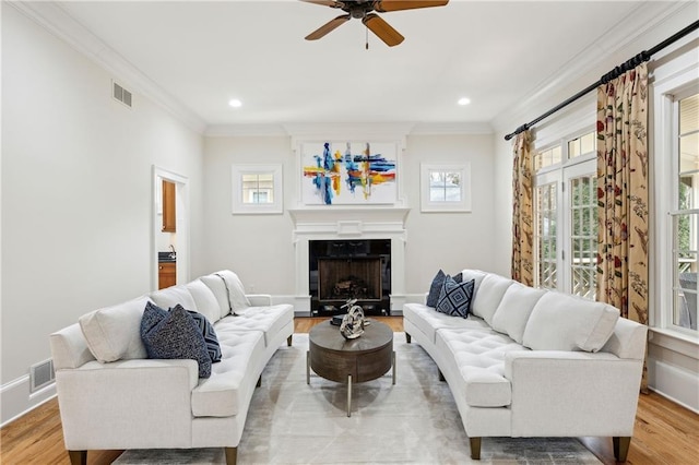 living room featuring light wood finished floors, visible vents, and a ceiling fan