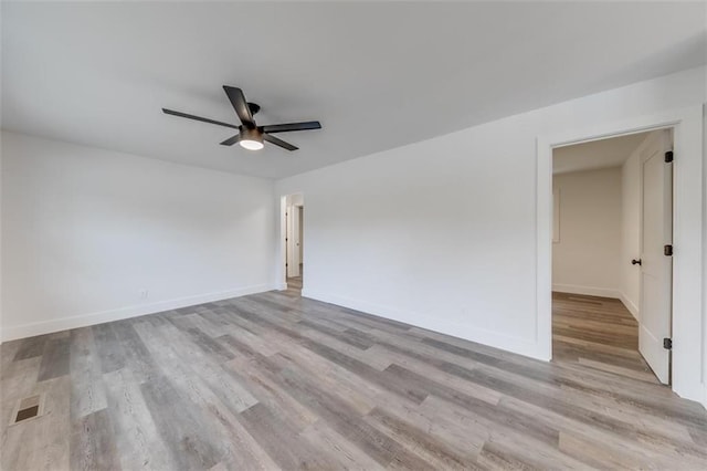 empty room featuring a ceiling fan, wood finished floors, and baseboards