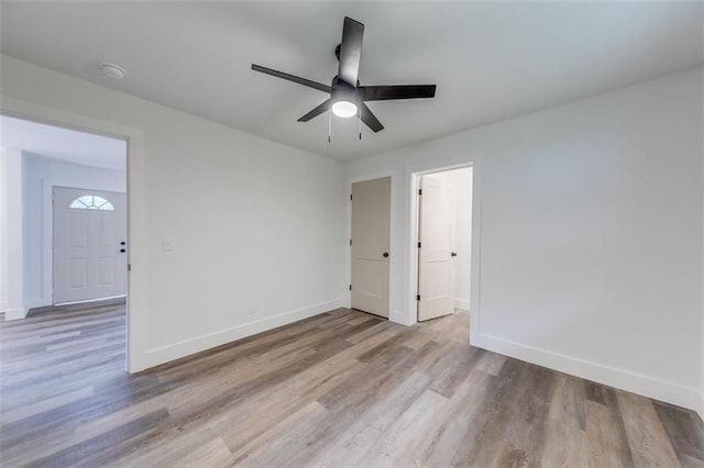 unfurnished room featuring baseboards, wood finished floors, ceiling fan, and a smoke detector