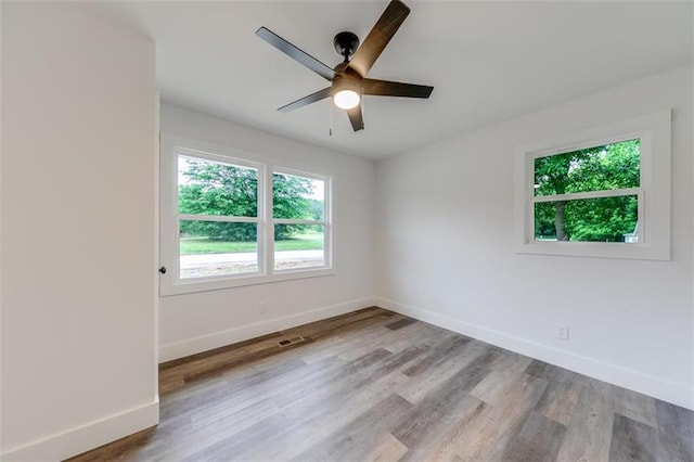 spare room with baseboards, wood finished floors, and ceiling fan