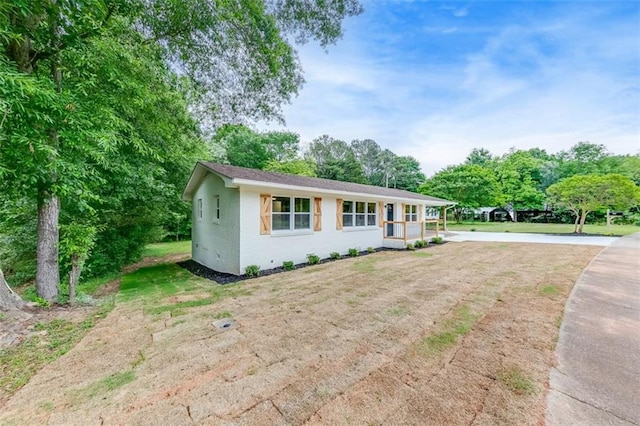 view of front of home featuring a front lawn and view of wooded area