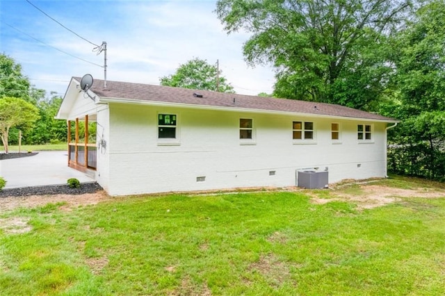 back of property with cooling unit, a yard, and crawl space