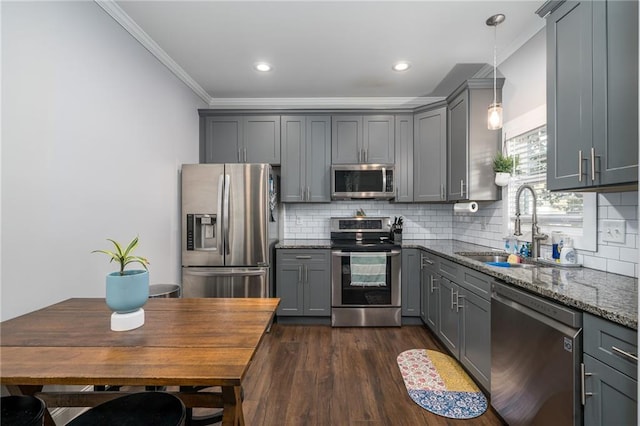 kitchen with gray cabinetry, dark wood-type flooring, stainless steel appliances, light stone counters, and decorative light fixtures