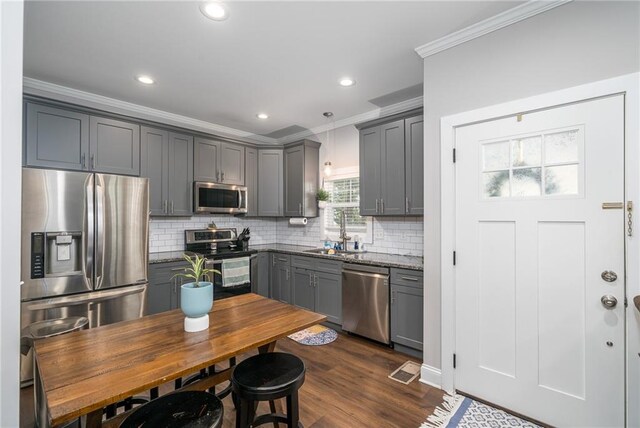 kitchen with gray cabinetry, dark stone countertops, dark wood-type flooring, and appliances with stainless steel finishes