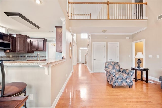 1979 Spivey Village Dr, Jonesboro, GA 30236 - kitchen featuring stainless steel microwave, a breakfast bar area, light wood-style floors, dark brown cabinets, and decorative backsplash