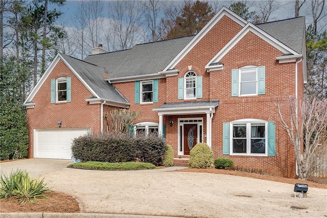 view of front facade with driveway, an attached garage, a chimney, and brick siding