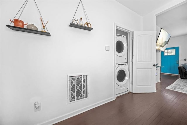 clothes washing area featuring stacked washing maching and dryer and dark wood-type flooring