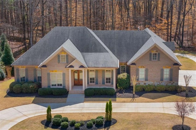 view of front facade with a front yard, brick siding, and a shingled roof