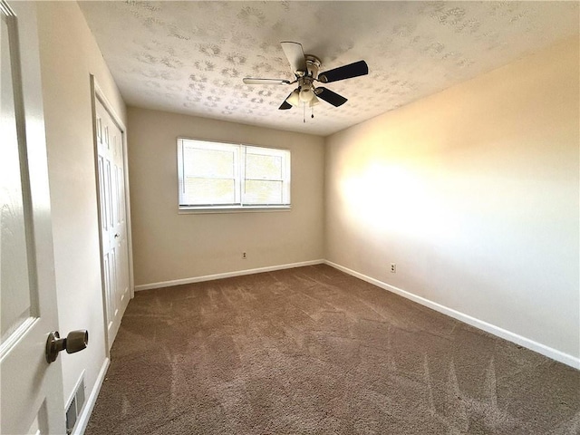 unfurnished bedroom with dark colored carpet, ceiling fan, a textured ceiling, and a closet