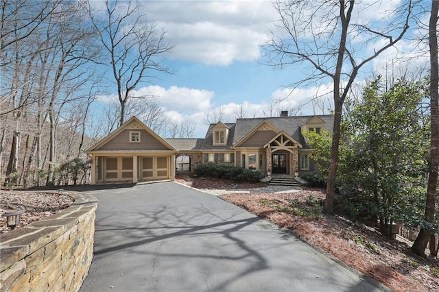 view of front of home featuring aphalt driveway, a garage, and a chimney