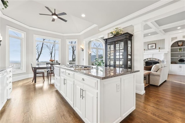 kitchen with a wealth of natural light, a stone fireplace, a center island, and a ceiling fan