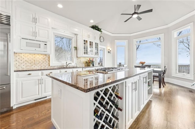 kitchen featuring built in appliances, plenty of natural light, a kitchen island, and dark wood-style flooring