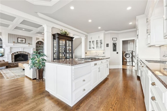 kitchen with dark stone counters, dark wood-style flooring, ornate columns, and washer and clothes dryer