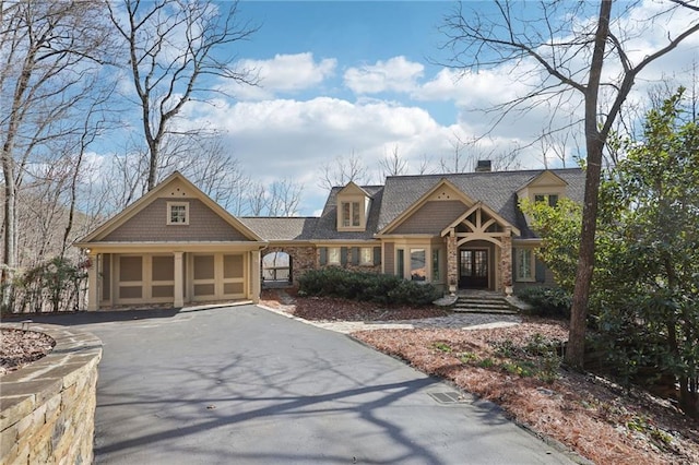 view of front of house with aphalt driveway, roof with shingles, french doors, a chimney, and an attached garage