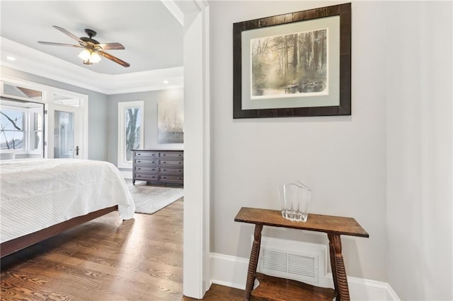 bedroom featuring visible vents, a raised ceiling, wood finished floors, baseboards, and access to exterior