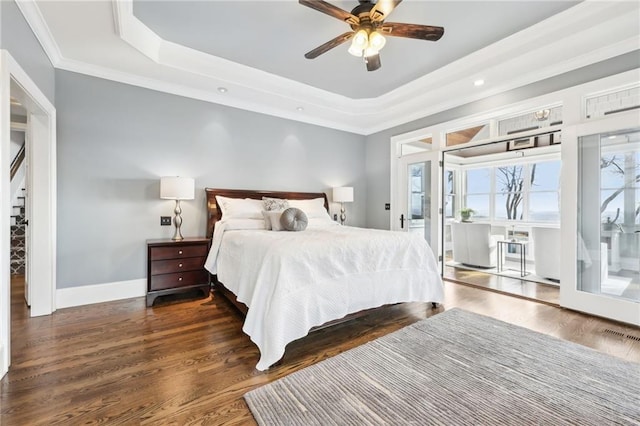 bedroom with a tray ceiling, baseboards, wood finished floors, and ornamental molding