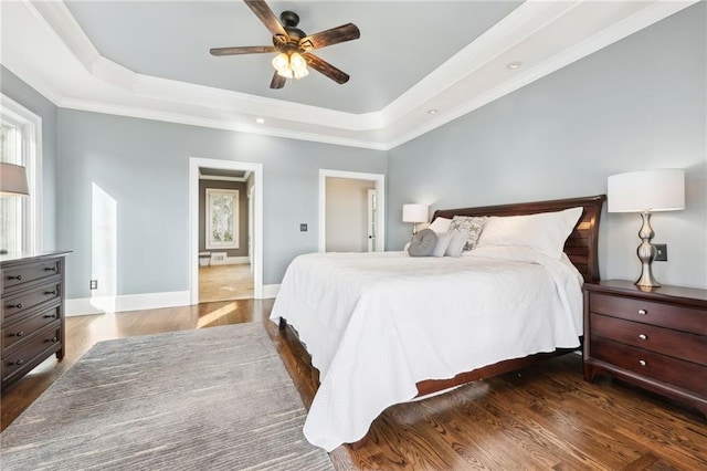 bedroom with a tray ceiling, baseboards, wood finished floors, and ornamental molding