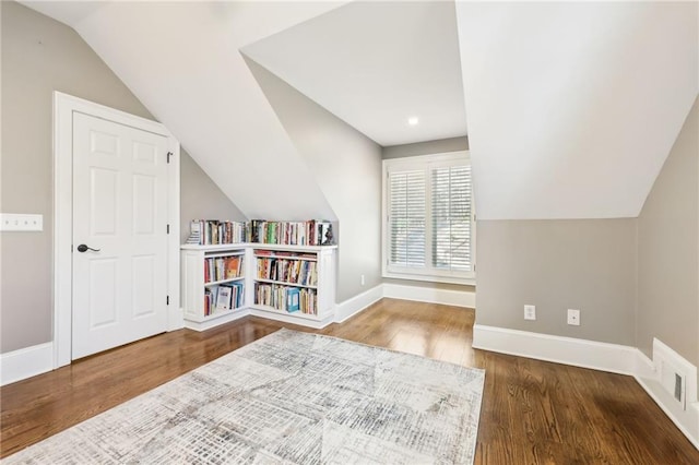 additional living space with visible vents, wood finished floors, baseboards, and lofted ceiling