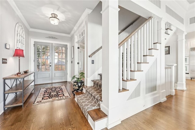 entryway with stairway, wood finished floors, ornate columns, ornamental molding, and french doors