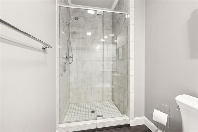 bathroom featuring baseboards, toilet, and a stall shower