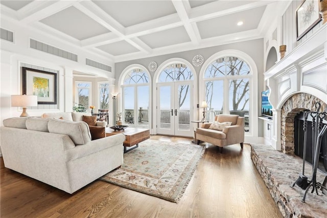 living area featuring visible vents, a fireplace with raised hearth, french doors, a towering ceiling, and wood finished floors