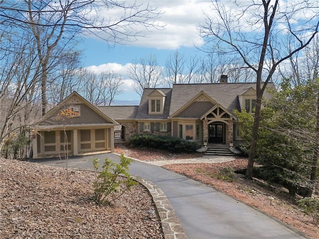 view of front of house featuring brick siding, a chimney, a garage, and roof with shingles