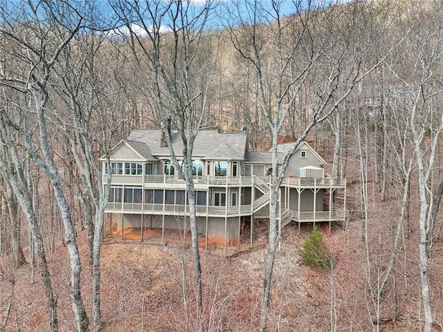 back of property with stairs, a deck, and roof with shingles