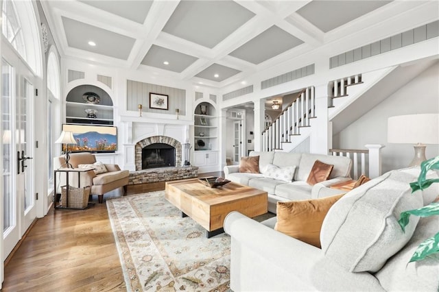 living room with built in features, wood finished floors, coffered ceiling, beam ceiling, and a fireplace