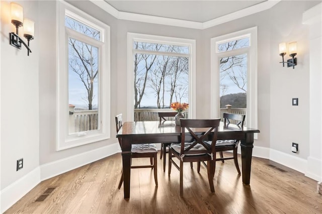 dining space featuring visible vents, crown molding, baseboards, and wood finished floors