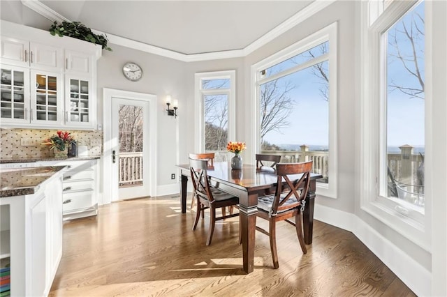 dining room with baseboards, light wood finished floors, and ornamental molding