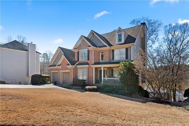 view of front facade with covered porch, brick siding, and driveway