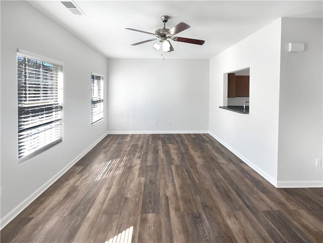 unfurnished room featuring wood finished floors, a ceiling fan, visible vents, and baseboards