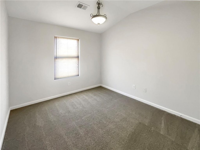 spare room with visible vents, baseboards, dark carpet, and vaulted ceiling