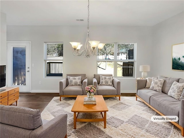 living room featuring a notable chandelier, baseboards, visible vents, and wood finished floors