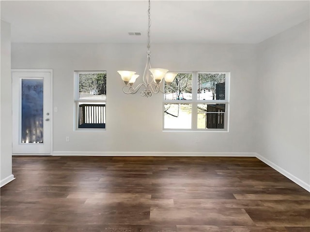 unfurnished dining area with visible vents, baseboards, an inviting chandelier, and wood finished floors